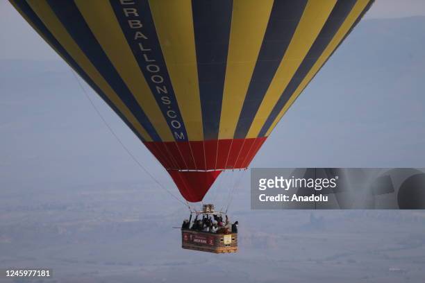 People ride on the gondola of a hot air balloon over the historical Cappadocia region, located in Central Anatolia's Nevsehir province, Turkiye on...