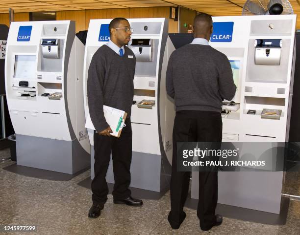 Staff members stand by the machine that processes the CLEAR airport biometric "fast pass" card during a roll-out of the system on February 11, 2008...