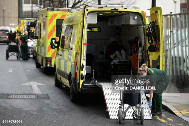 Paramedic folds a wheelchair used to transport a patient into an ambulance outside the Royal London hospital in east London on January 4, 2023. - UK...