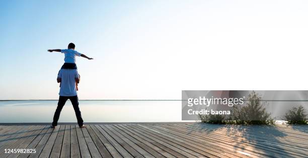 father with his son enjoying lake view - carrying on shoulders stock pictures, royalty-free photos & images