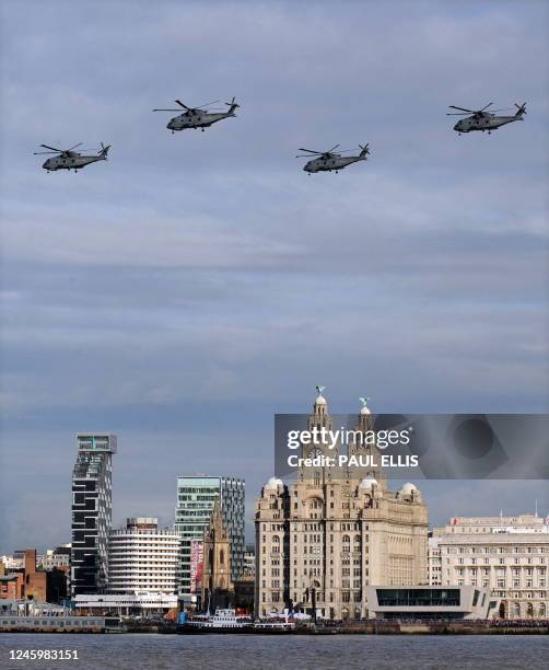 Military helicopters fly over the Liver Buildings and British aircraft carrier HMS Illustrious in the River Mersey in Liverpool, north-west England,...