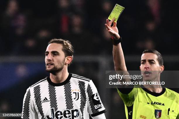 Italian referee Giovanni Ayroldi gives a yellow card to Juventus' French midfielder Adrien Rabiot during the Italian Serie A football match between...