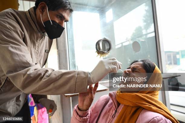 Health worker collects a nasal swab sample from a woman to test for the Covid-19 coronavirus at a hospital in Amritsar on January 5, 2023.