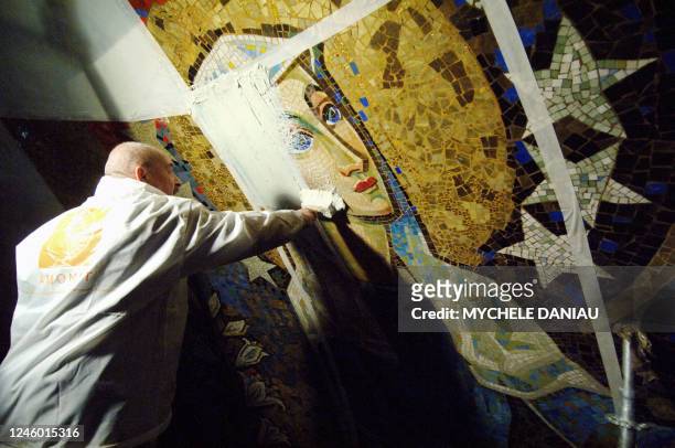 Painter covers with a renovating product Saint Therese mosaic by artist Pierre Gaudin in the crypt of St Therese basilic in Lisieux, northwestern...