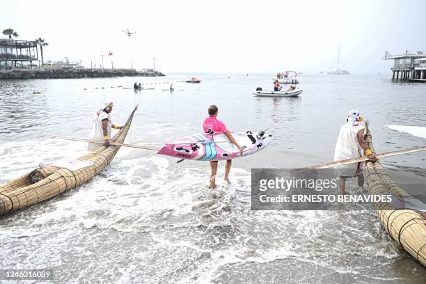 Itziar Abascal gets into the ocean next to two men dressed as people from the Moche civilization paddling their "Caballitos de Totora", a type of...