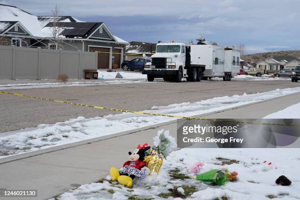 The wind blows flowers, part of a makeshift memorial as a police crime scene trailer sits outside the home of Michael Haight on January 5, 2023 in...