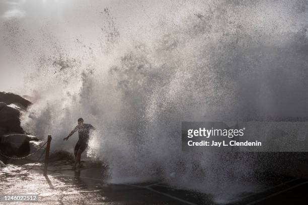 Redondo Beach, CA Slade Watson,15 from Hermosa Beach, runs as waves come crashing over the breakwall of Redondo Beach, CA, Harbor, where kids played...