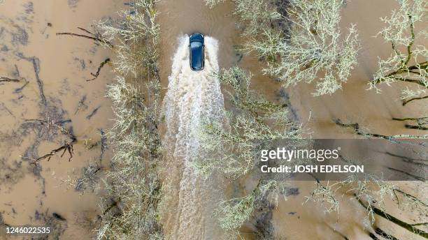 Vehicle drives on a flooded road in Sebastopol, California, on January 5, 2023. - Excessive rain, heavy snow and landslides are expected to wallop...