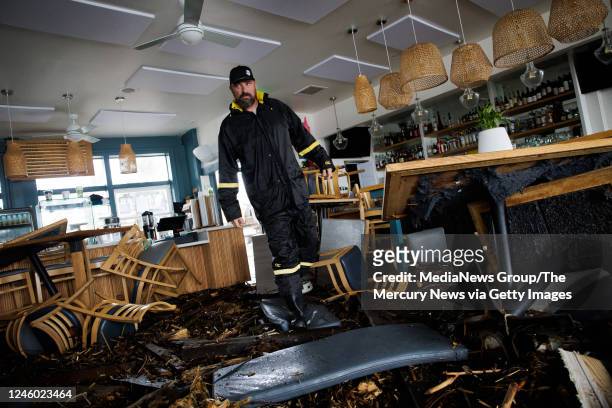 January 05: Zelda's on the Beach co-owner Joshua Whitby surveys the damage caused by a surging ocean smashing debris through the windows and walls...