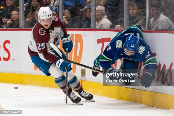 Quinn Hughes of the Vancouver Canucks gets upended by Logan O'Connor of the Colorado Avalanche after playing the puck during the first period in NHL...