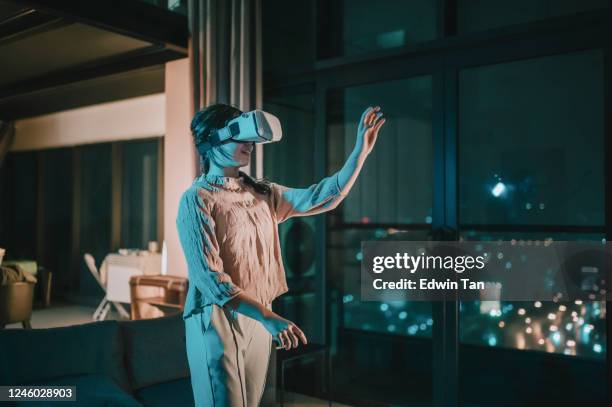 an asian chinese teenager girl put on vr goggle and experiencing 3d virtual gaming experience in living room - film lighting equipment stock pictures, royalty-free photos & images