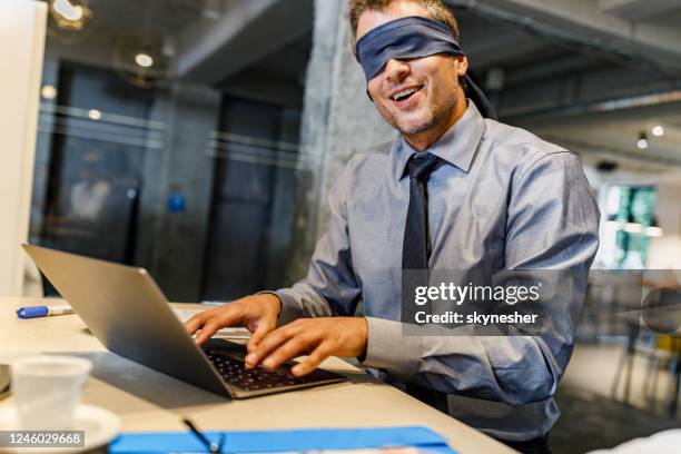 un hombre de negocios con los ojos vendados incapaz de ver la realidad por computadora en la oficina. - ignorancia fotografías e imágenes de stock