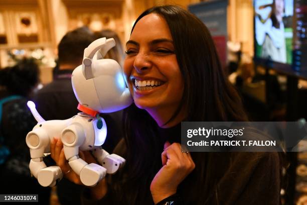 An attendee plays with the WowWee Dog-E, a robotic dog unique to every user, at ShowStoppers during the Consumer Electronics Show in Las Vegas,...