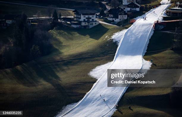 Skiers descend the slopes of the Rohrmoos skiing area covered in artificial snow as grass covers the rest of the hill on either side on January 6,...