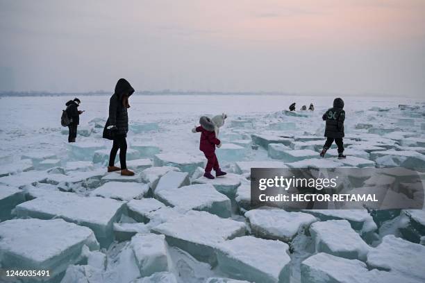 People walk on blocks of ice on the frozen Songhua river in Harbin, in China's northeastern Heilongjiang province, on January 6, 2023.