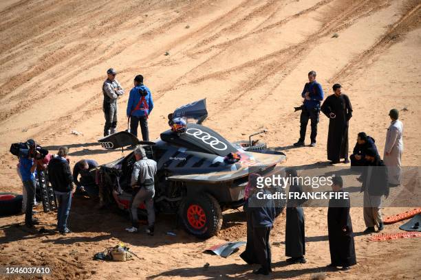 Audi's hybrid driver Carlos Sainz of Spain walks around his car after a crash during the Stage 6 of the Dakar 2023 between Ha'il and Al Duwadimi,...
