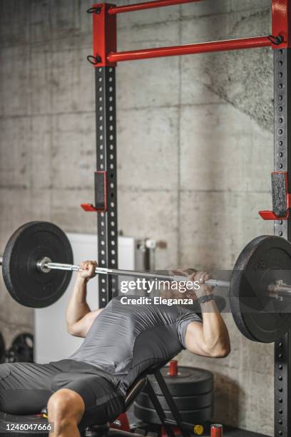 deportista haciendo prensa de banco, atleta durante el entrenamiento en el gimnasio profesional, levantamiento de pesas para bíceps, pectorales y músculos de la espalda - bench press weights fotografías e imágenes de stock