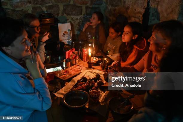 People enjoy their dinner with a flashlight and candles during power outage on Orthodox Christmas Eve, in Lviv, Ukraine, on January 6, 2023....