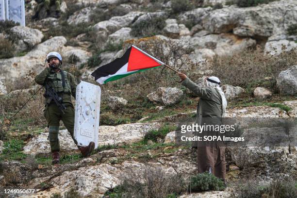 An old Palestinian protester waves Palestinian flag while he confronts the Israeli soldiers during the demonstration against Israeli settlements in...