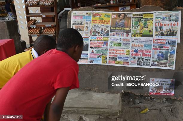 Local residents read the headlines of local newspapers after the release of 46 Ivorian soldiers arrested in July 2022 in Mali, in Abidjan on January...