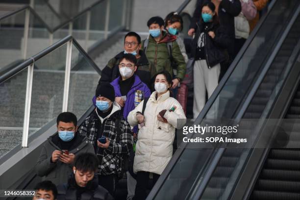 Passengers wearing masks go down the escalator at the railway station. Around 6.3 million passenger trips are expected to be made across China on...