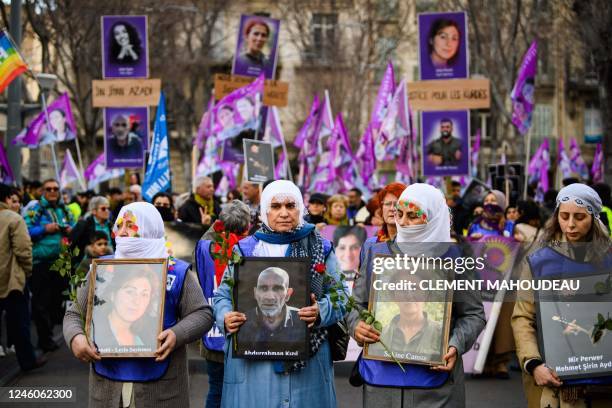 Demonstrators hold portraits of the Kurdish activists killed in 2013 and portraits of victims of the shooting Rue d'Enghien in Paris on December 23,...