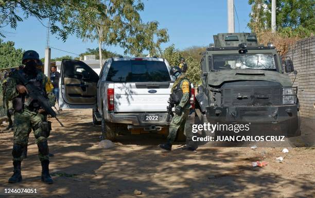 Soldiers stand guard next to a vehicle of the Army destroyed during the operation to arrest Ovidio Guzman, aka "El Raton" , son of jailed drug...