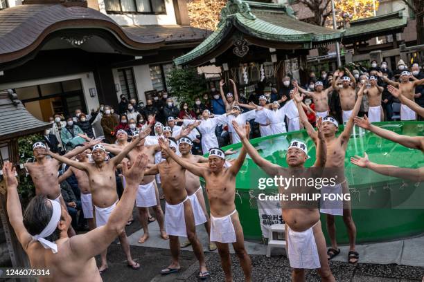 Shinto believers of the Teppozu Inari Shrine warm up before taking a bath in cold water to purify their souls and bodies during a New Year ritual in...