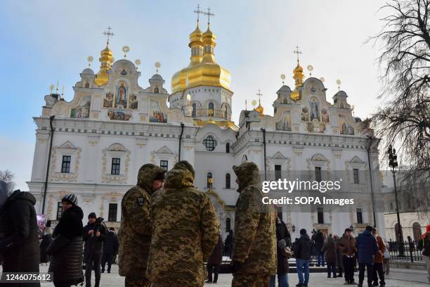 People and soldiers in the foreground stand against the background of the Assumption Cathedral during the Christmas service, which was led by the...