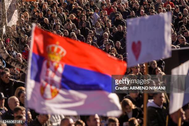 Kosovo Serbs hold a Serbian flag and signs as they take part in a demonstration in Strpce on January 8 after a gunman shot and wounded two Serbs, one...