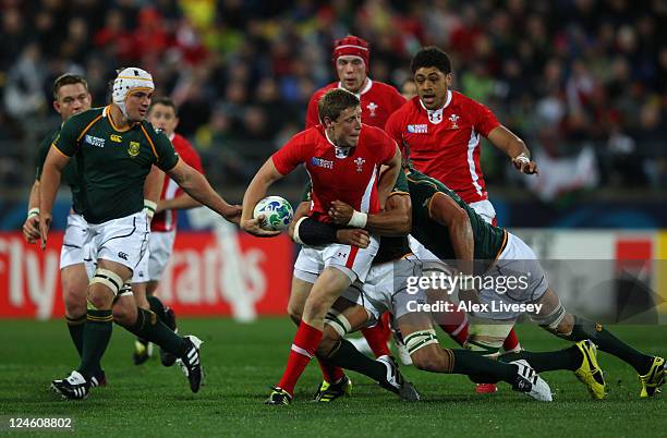 Rhys Priestland of Wales looks to offload as he is wrapped up by the South Africa Defence during the IRB 2011 Rugby World Cup Pool D match between...