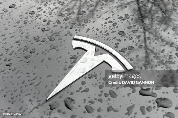 Raindrops are seen next to the Tesla logo on the bonnet of a Tesla electric car in Berlin's Kreuzberg district on January 8, 2023. - Tesla has...