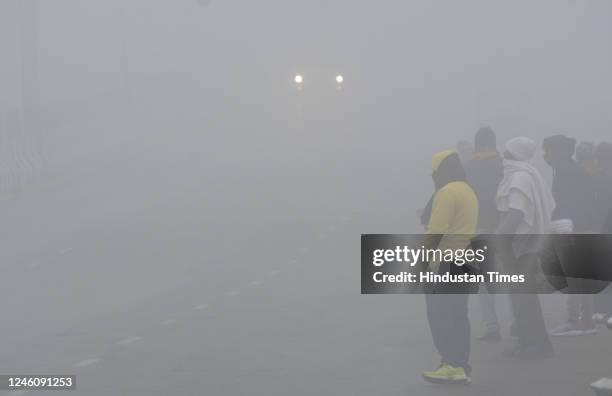 Commuters are seen wearing warm clothes during a cold and foggy morning at National Highway 9 near Dasna, on January 8, 2023 in Ghaziabad, India. The...