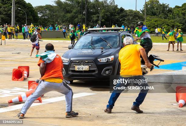 Supporters of Brazilian former President Jair Bolsonaro attack a vehicle of the Military Police during clashes outside Planalto Presidential Palace...