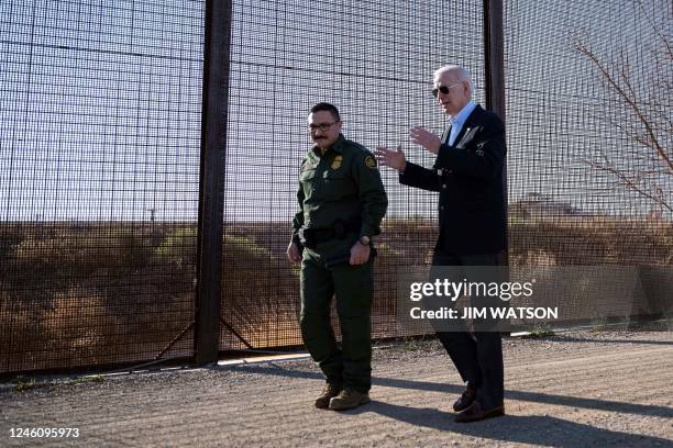 President Joe Biden speaks with a member of the US Border Patrol as they walk along the US-Mexico border fence in El Paso, Texas, on January 8, 2023....