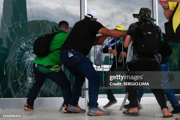 Supporters of Brazilian former President Jair Bolsonaro break a window as they invade Planalto Presidential Palace in Brasilia on January 8, 2023. -...