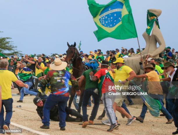 Military Police officer falls from his horse during clashes with supporters of Brazilian former President Jair Bolsonaro after an invasion to...