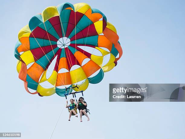 couple are parasailing in sky. - parascending stock pictures, royalty-free photos & images