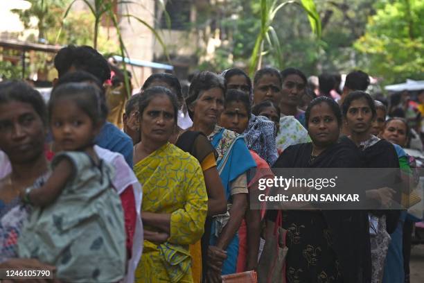 People stand in a queue as they wait in front of a government ration shop to collect free gift hampers on the occasion of the harvest festival of...