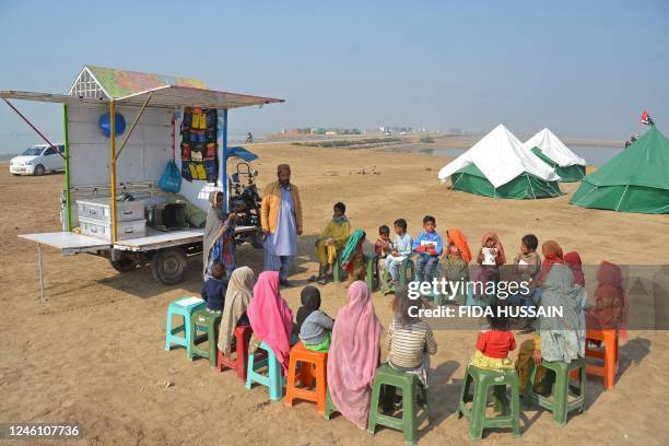 Internally displaced flood-affected children attend a mobile school class near makeshift camp in the flood-hit area of Dera Allah Yar in Jaffarabad...