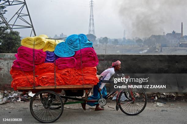 Worker pulls his cycle rickshaw loaded with bundles of cloth in Dhaka on January 9, 2023.