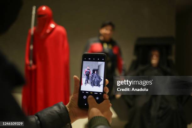 Man takes a photo with a cell phone of another man during the exhibition "Mutante" by sculptor Ramiro Sirpa in La Paz, Bolivia on December 22, 2022....