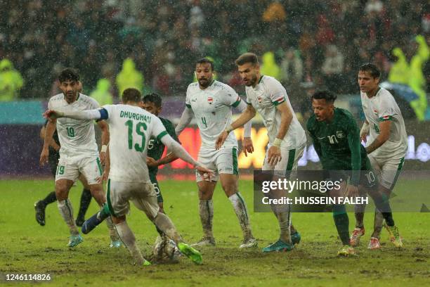 Iraq's left winger Dhurgham Ismail and Saudi Arabia's midfielder Hussein al-Issa fight for the ball on a muddy pitch during the Arabian Gulf Cup...