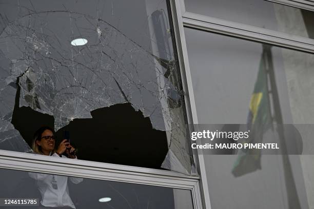 Woman takes a picture of a broken window at Planalto Palace in Brasilia on January 9 a day after supporters of Brazil's far-right ex-president Jair...