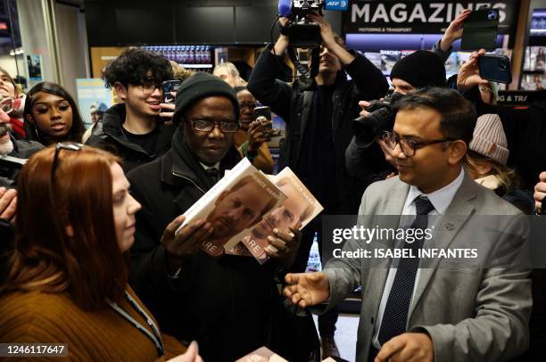 Members of the press gather around customers arriving during a special midnight opening event for the release of the book "Spare", by Britain's...