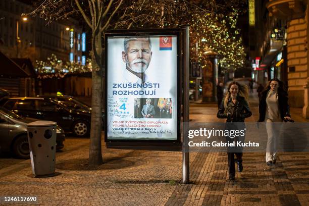 People walk past an election campaign poster for Army General Petr Pavel, former chairman of NATOs military committee placed at the street on January...