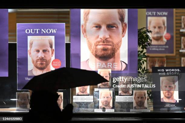 Pedestrian holding an umbrella walks past Waterstones' flagship Piccadilly bookshop advertising the release of "Spare" by Britain's Prince Harry,...