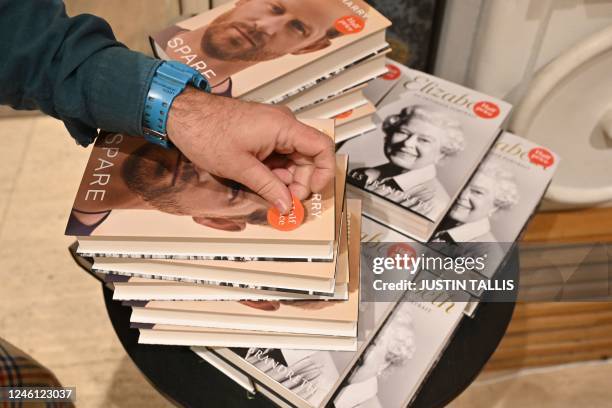 Bookseller puts a half price tag on copies of "Spare" by Britain's Prince Harry, Duke of Sussex, stacked on top of copies of a book about Britain's...