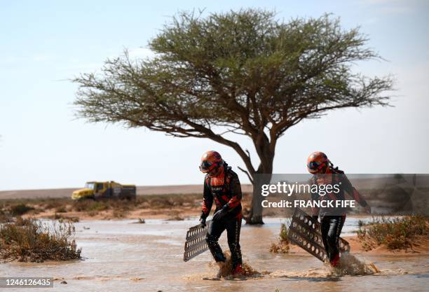 Czech Republic's truck co-driver Frantisek Tomasek and mechanic David Svanda try to get their truck out of the mud during Stage 9 of the Dakar 2023...