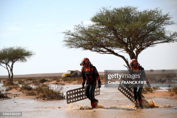 Czech Republic's truck co-driver Frantisek Tomasek and mechanic David Svanda try to get their truck out of the mud during Stage 9 of the Dakar 2023...